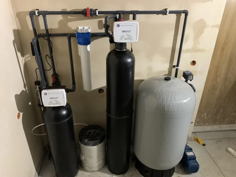 Czarne kolumny stacji uzdatniania wody z obudowami filtrów wstępnych w domu prywatnym